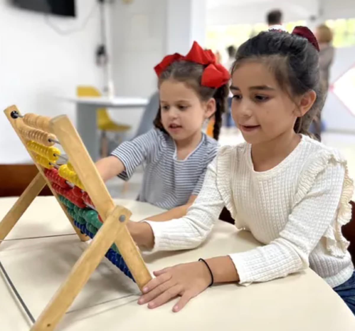 Dos niñas aprenden a contar con un ábaco de madera