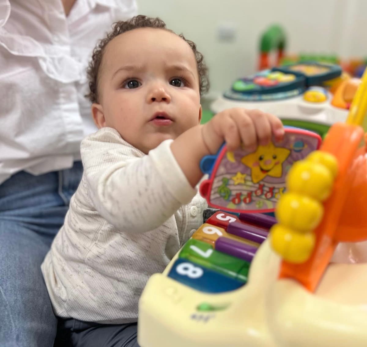 Bebé toca un piano de juguete