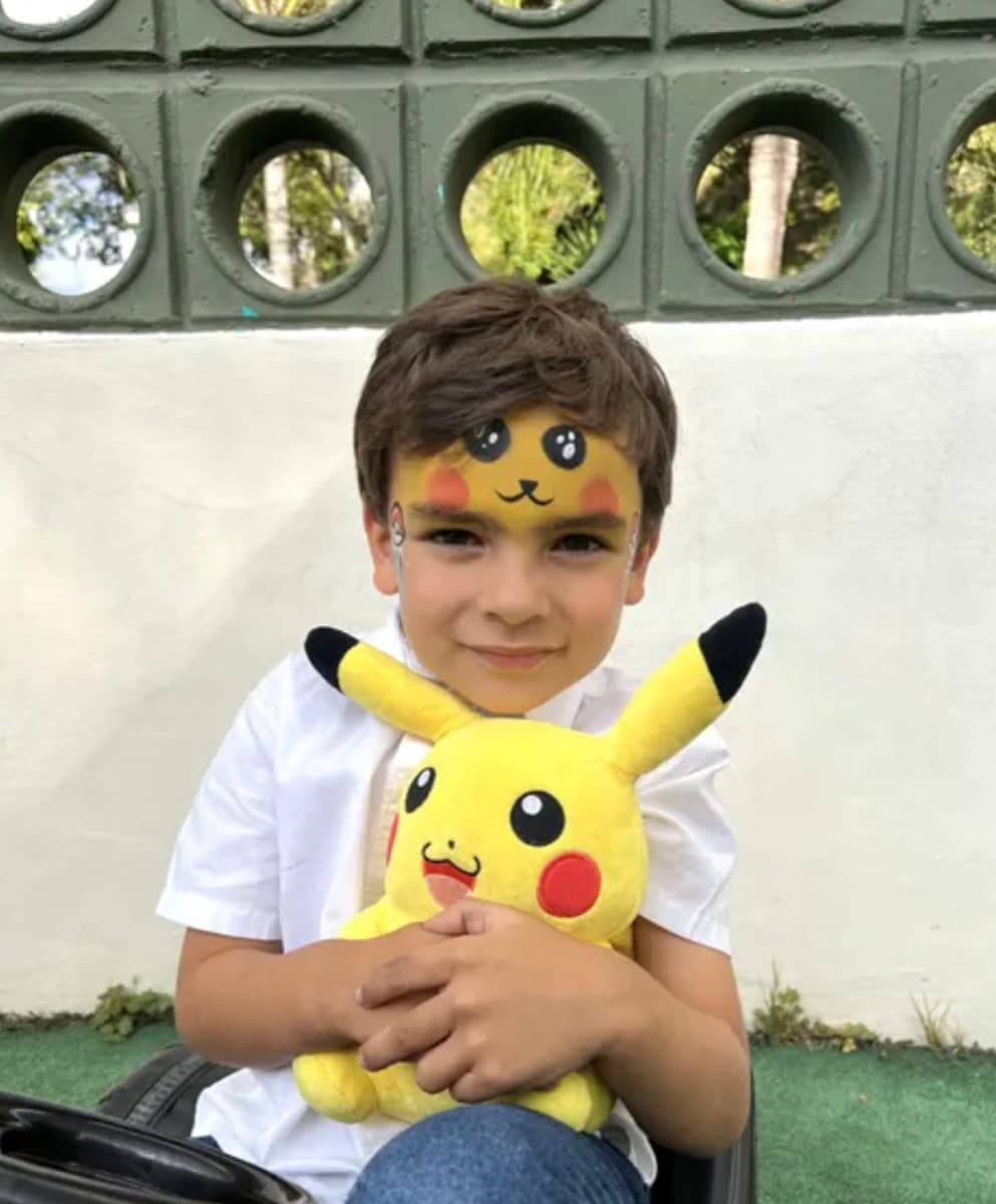 Niño con pintacaritas abraza su peluche en el patio de Italo Kids
